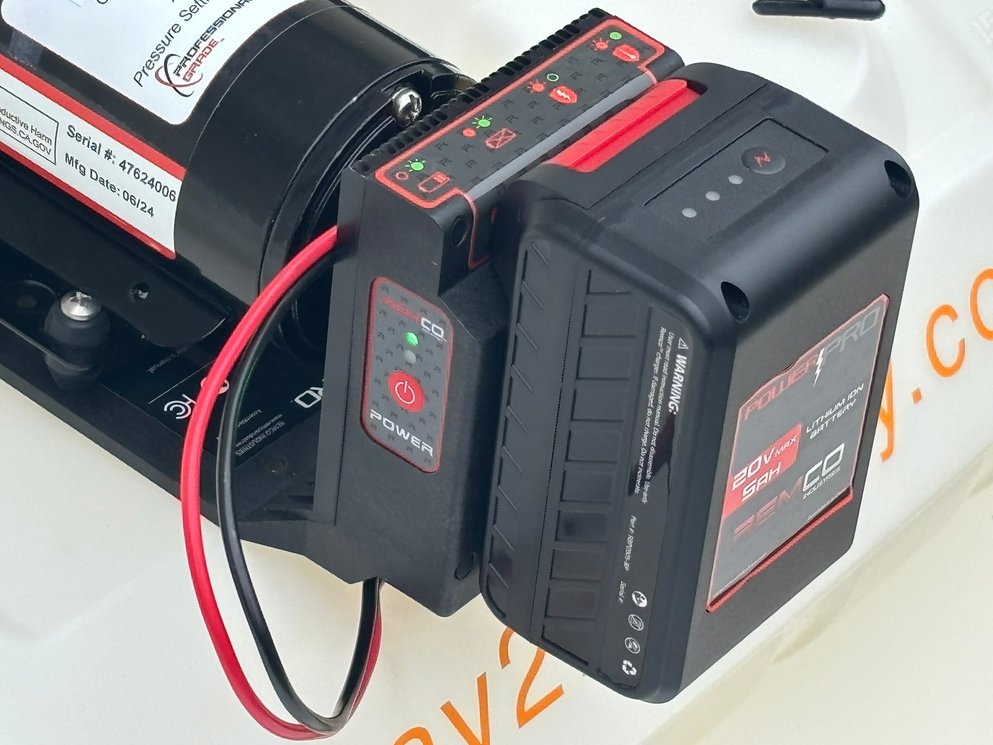 Black lithium ion battery is attached to controller with indicator lights which is wired to black pump assembly